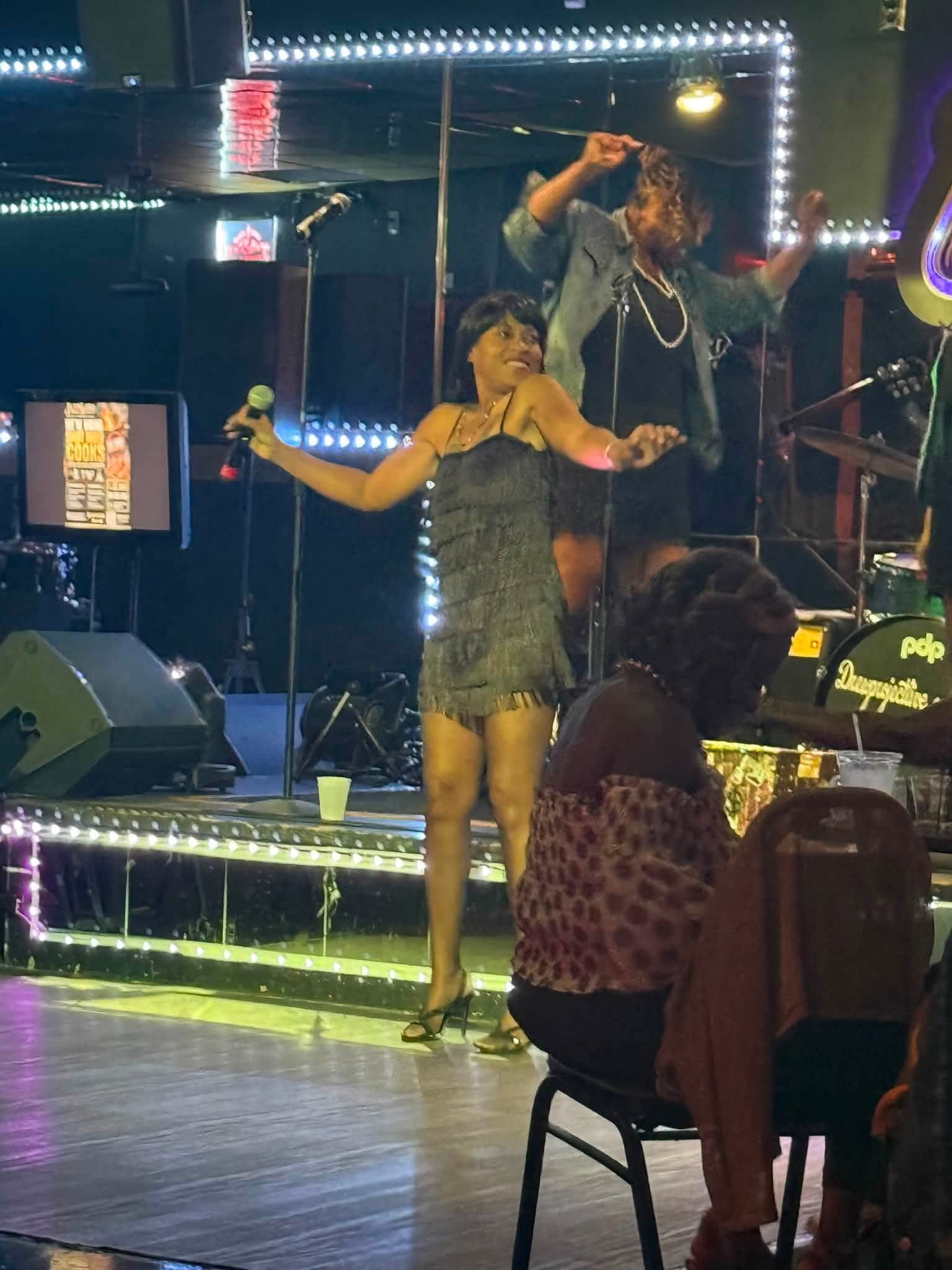 1 Tyme in a black outfit performing with her band